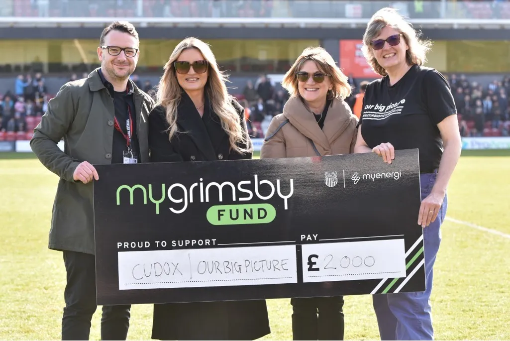 Cudox and the Myenegi team shown holding a cheque for the therapy play room project