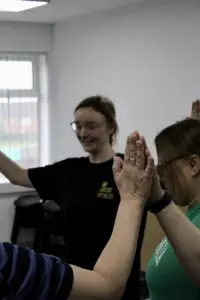 Outside in project - services users and trainers joining hands in a circle - side view