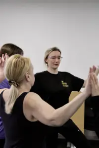 Outside in project - services users and trainers joining hands in a circle - portrait
