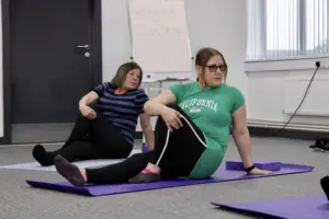 Outside in project service users performing stretches on yoga mats - close up